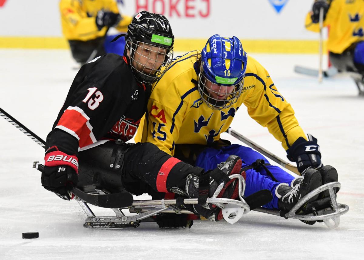 Two Para ice hockey players on sleds battling to get the puck