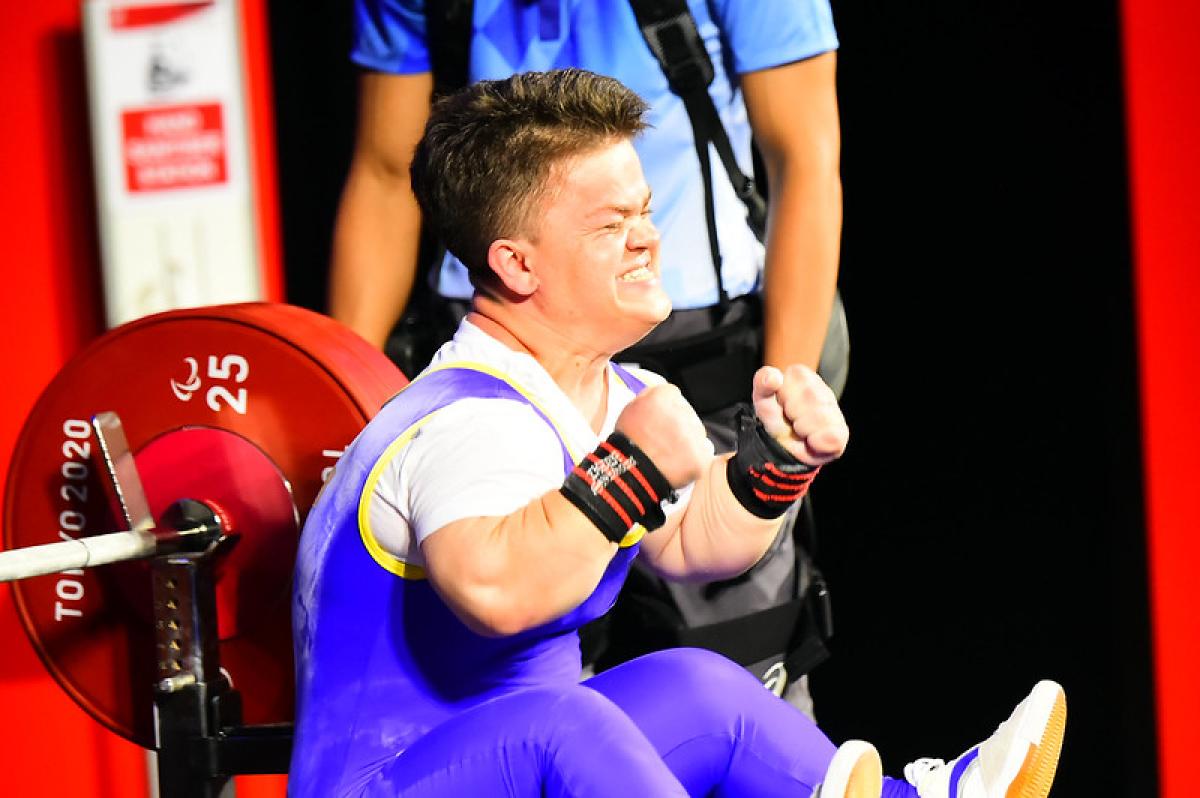 A short stature woman celebrating on a bench press