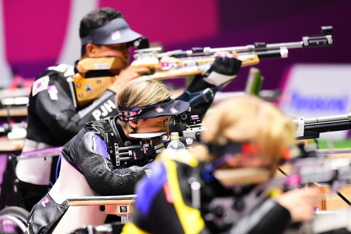 A woman competing in a shooting rifle competition between a male and a female shooter