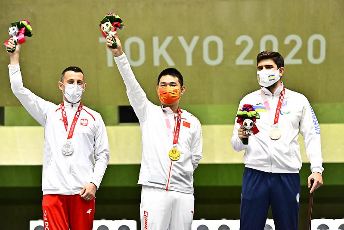 Three men standing on a podium with their medals