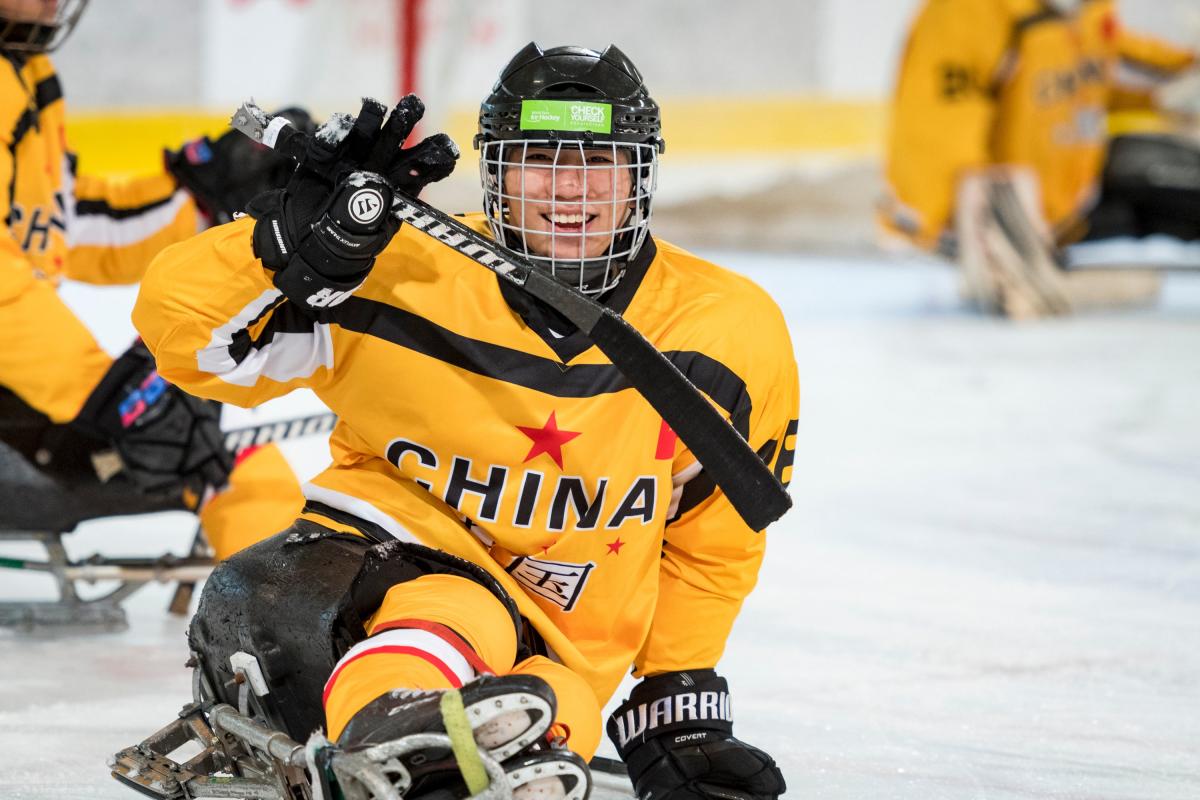 A Para ice hockey player celebrates scoring a goal with a smile on his face