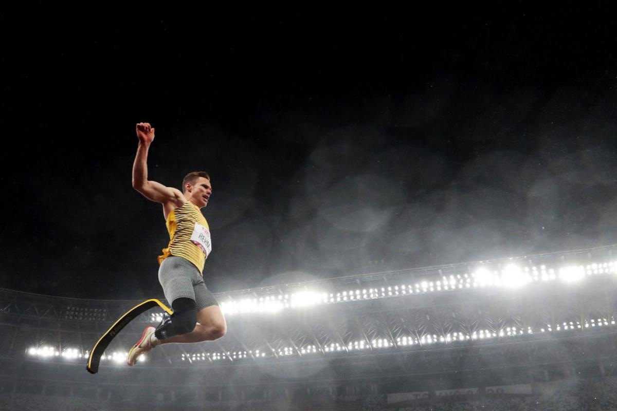 A man with a prosthetic leg jumping in a stadium