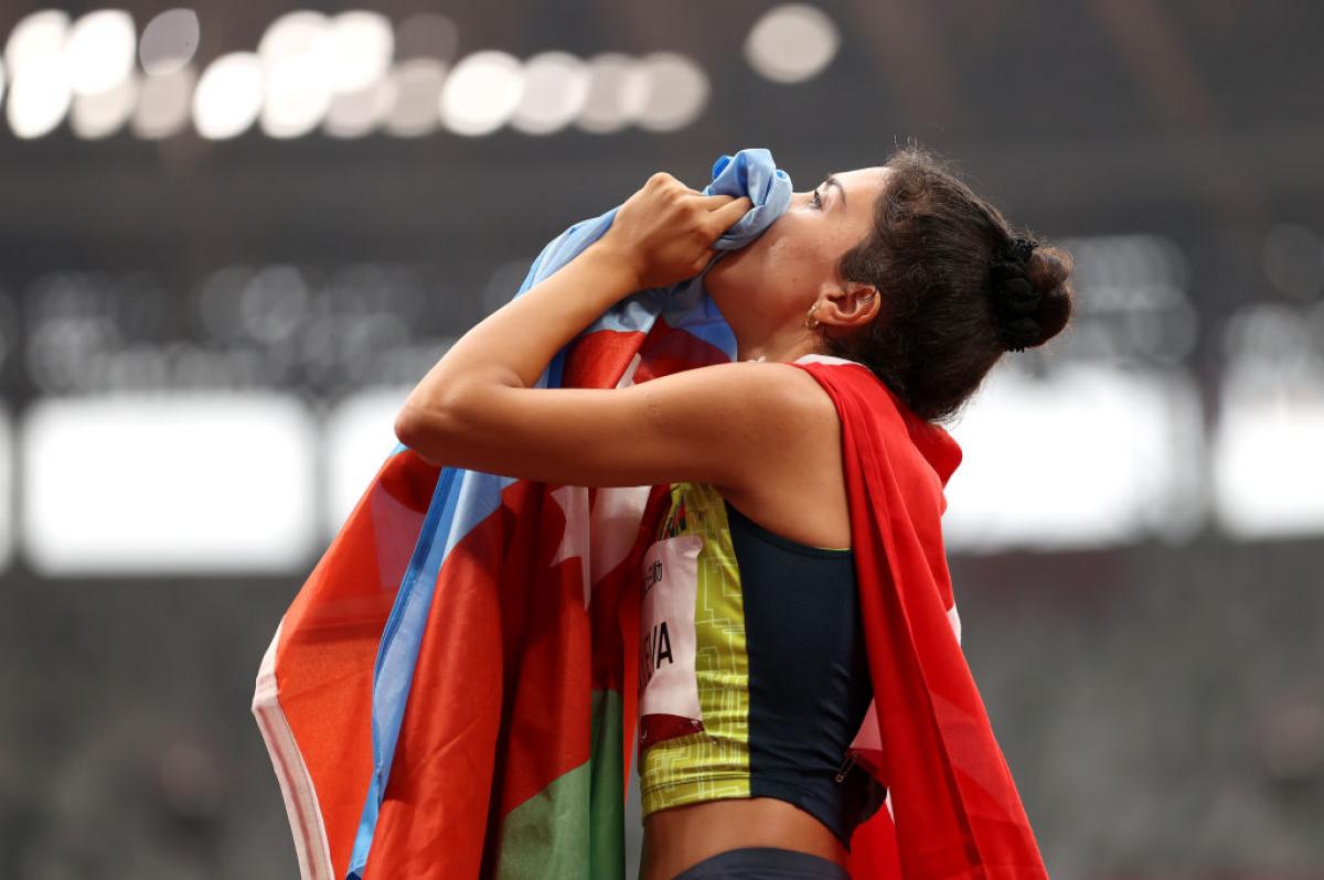 A female Para athletics athlete holding the flag of Azerbaijan