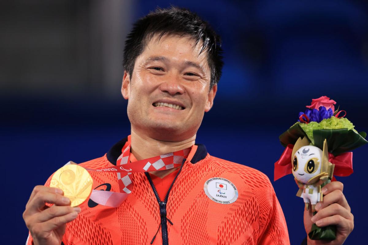 Shingo Kunieda holds his gold medal and mascot on podium