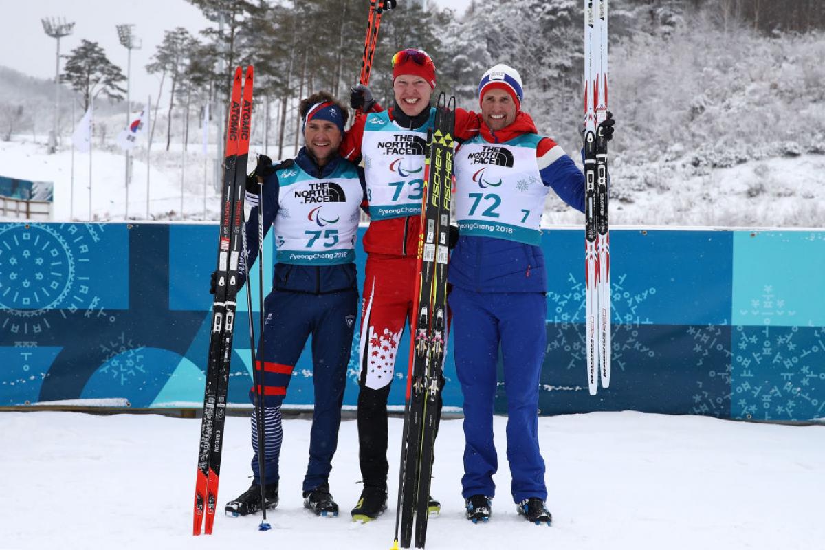 Three men standing on the snow with their skies 