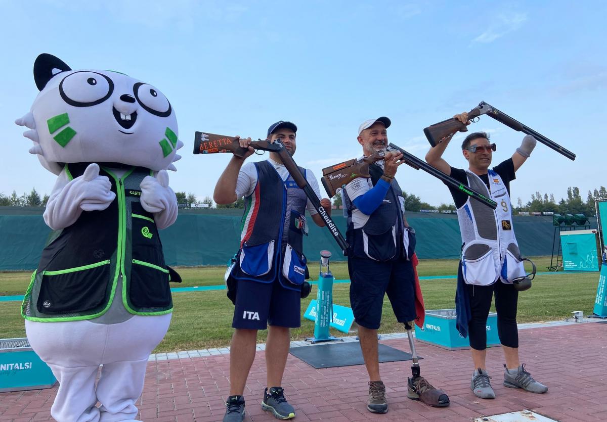 Three men standing with their shotguns near a person dressed as a mascot cat in a shooting range