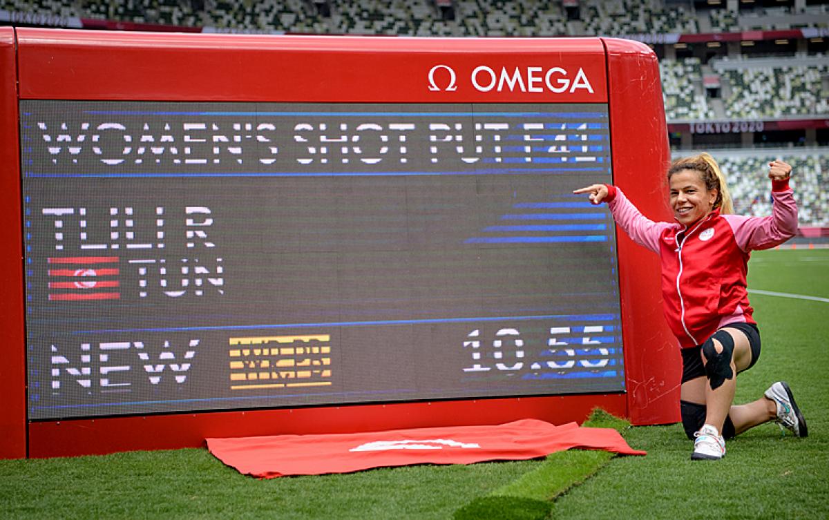 THE CHAMP: Raoua Tlili of Tunisia poses next to the digital scoreboard showing her World record in the women's shot put F41 at Tokyo 2020 Paralympic Games. 