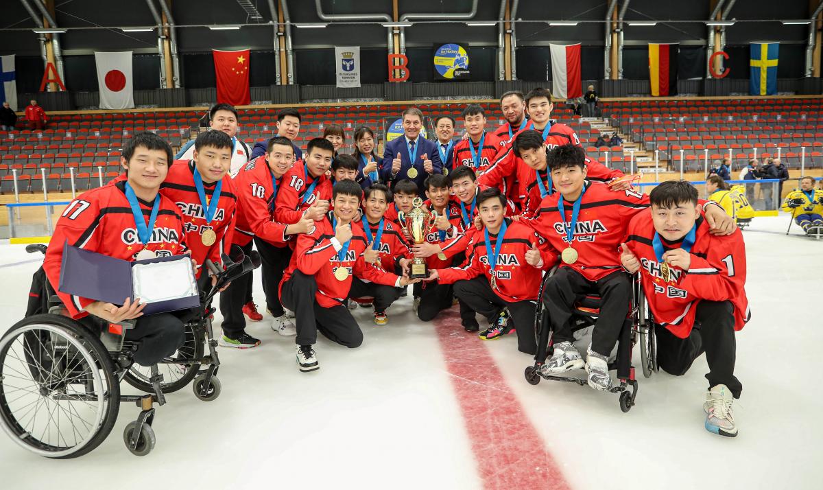 Para ice hockey players smiling and posing for a photo with the trophy and medals