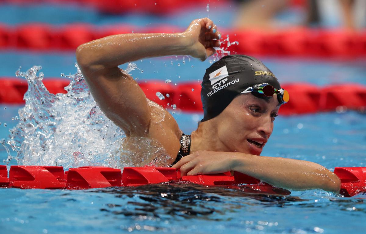 A woman celebrates in the pool with the right arm held high