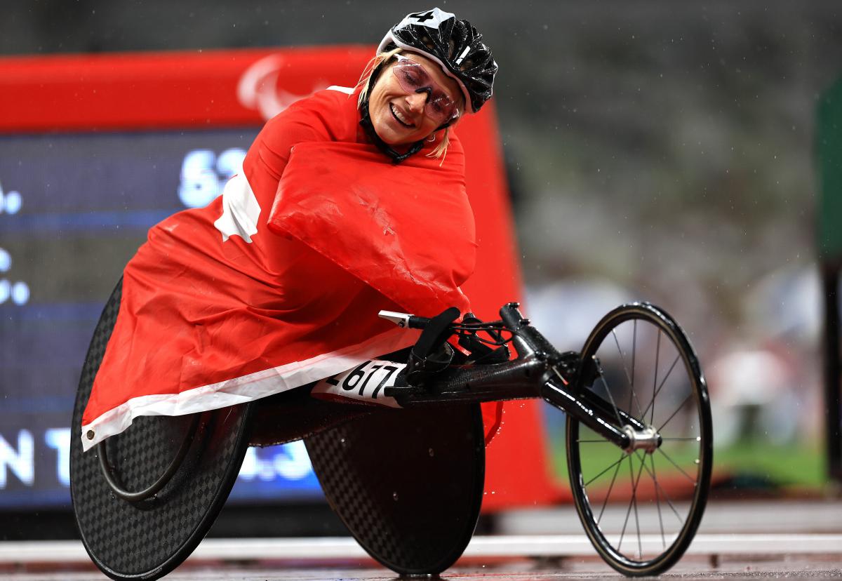 A woman sitting in a wheelchair wrapped around with the Swiss flag