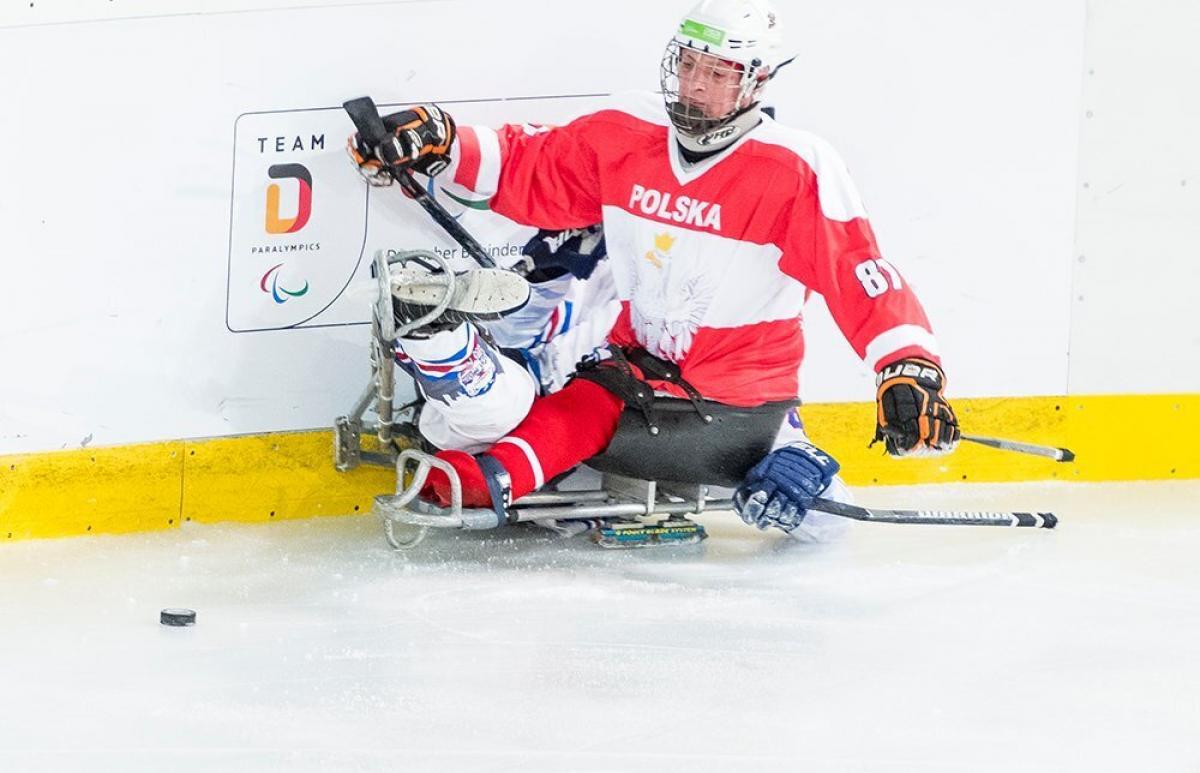 Para ice hockey player pushing another player to the fence