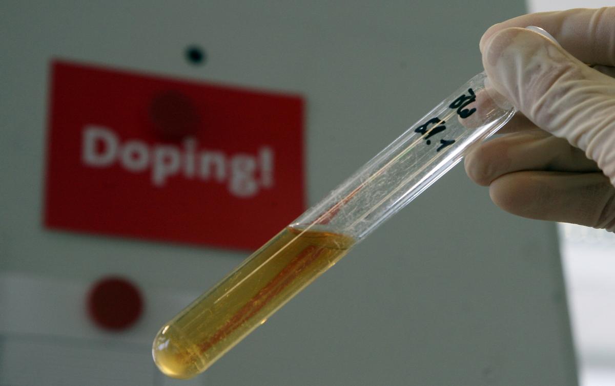 A test tube with a urine sample with a sign that says; "Doping!," behind it