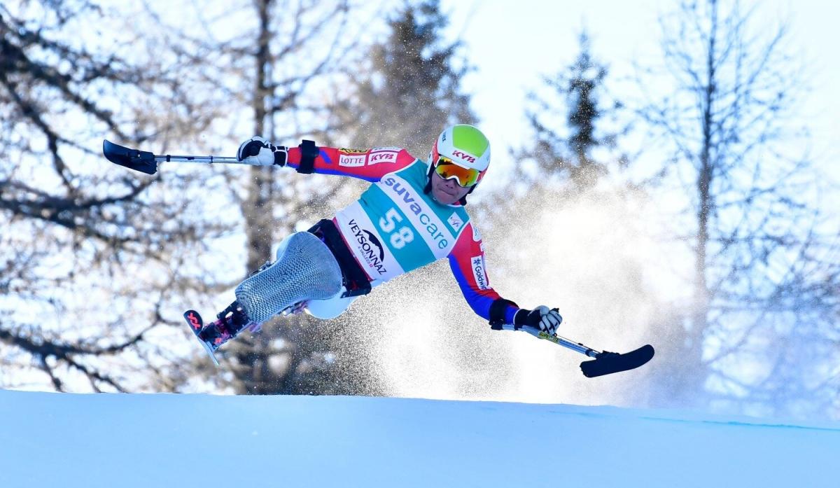 A man competes in Para Alpine skiing on a monoski on a sunny day