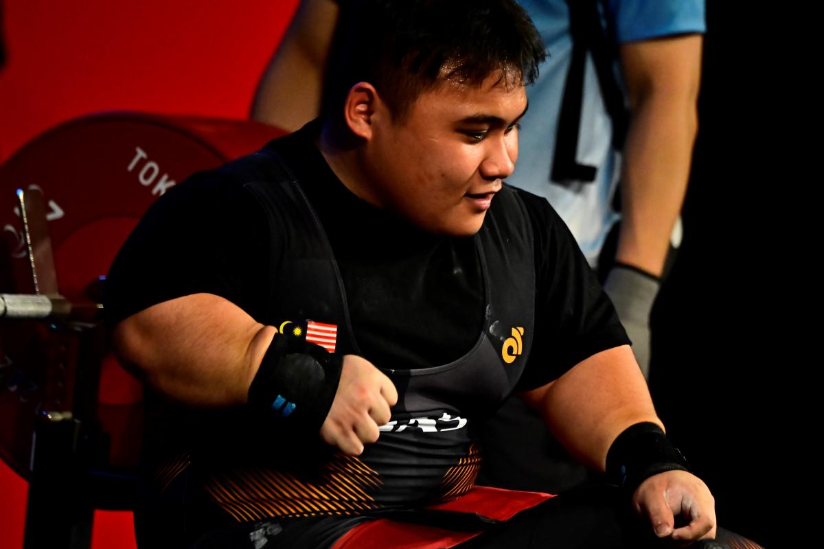 A man sitting on the bench after lifting the bar.