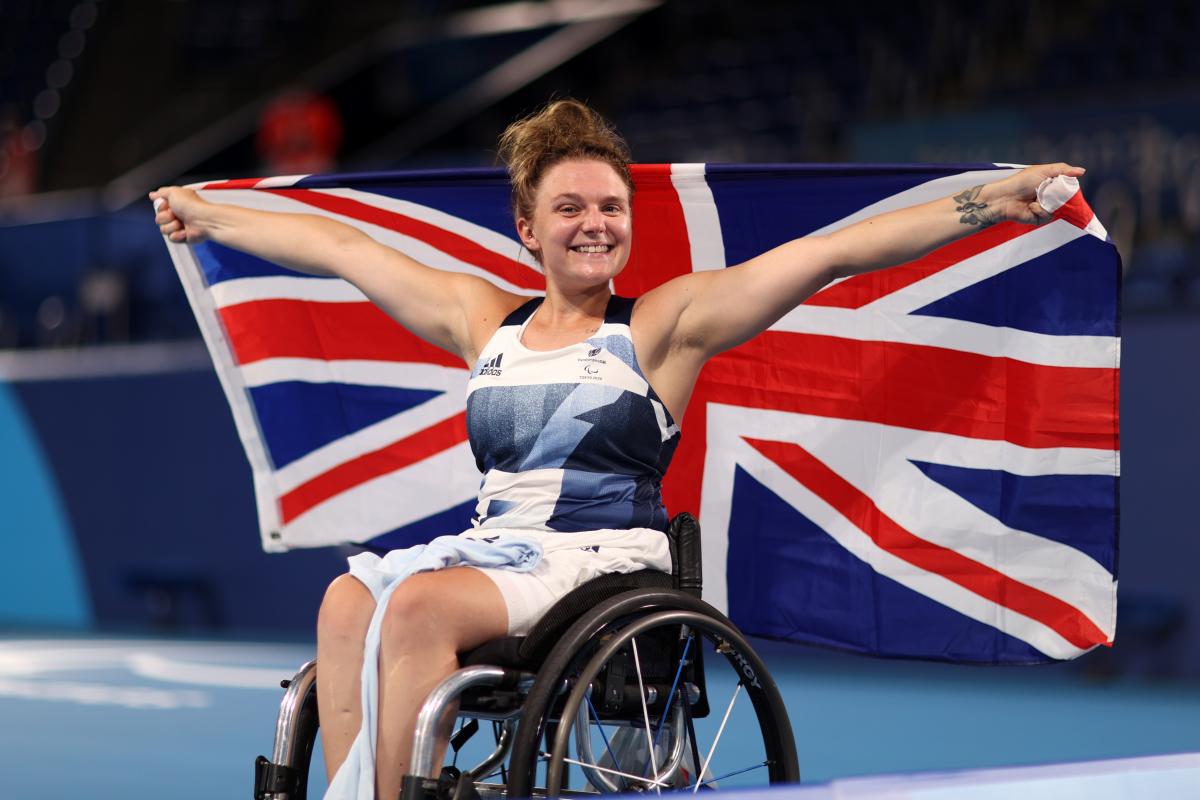 Jordanne Whiley smiles to the camera while holding the British flag