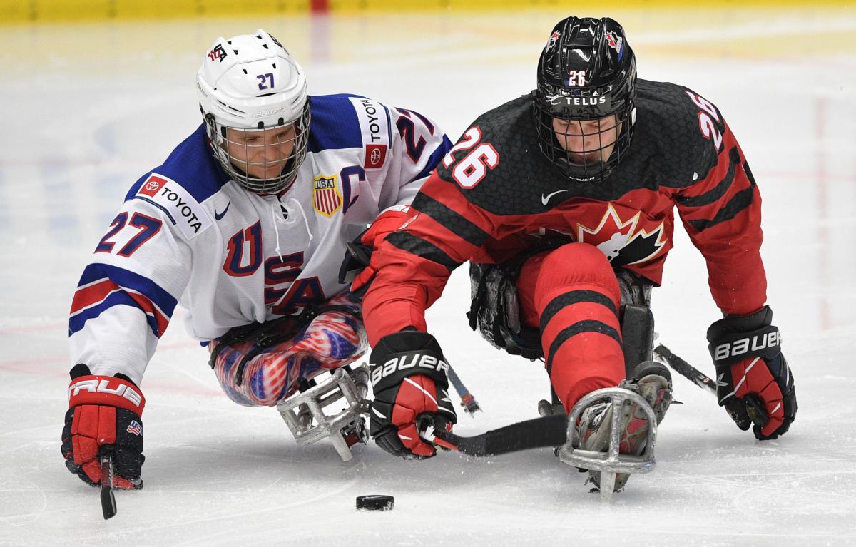 Two Para ice hockey players fighting to get the puck