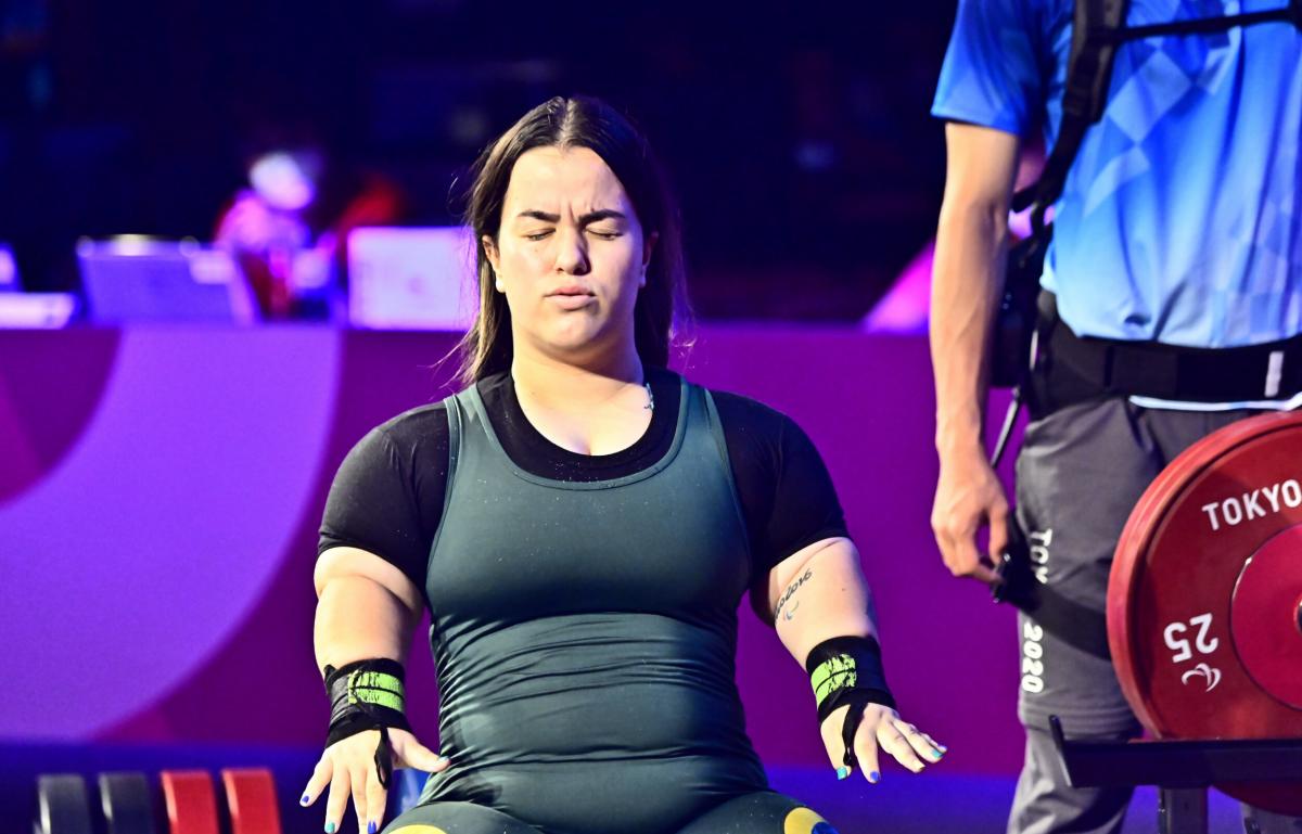 A woman standing with her eyes closed and her arms stretched with fists wide-open.