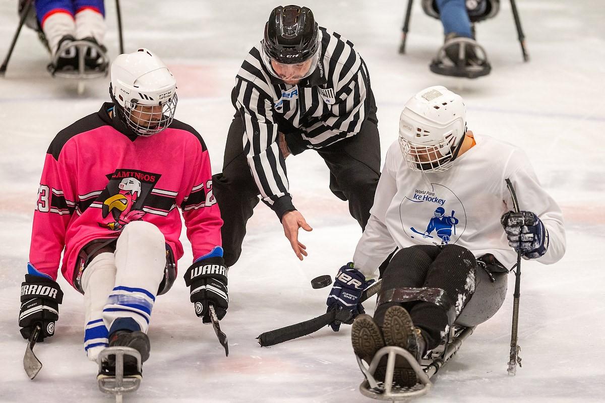 Two Para ice hockey players with a referee in the middle
