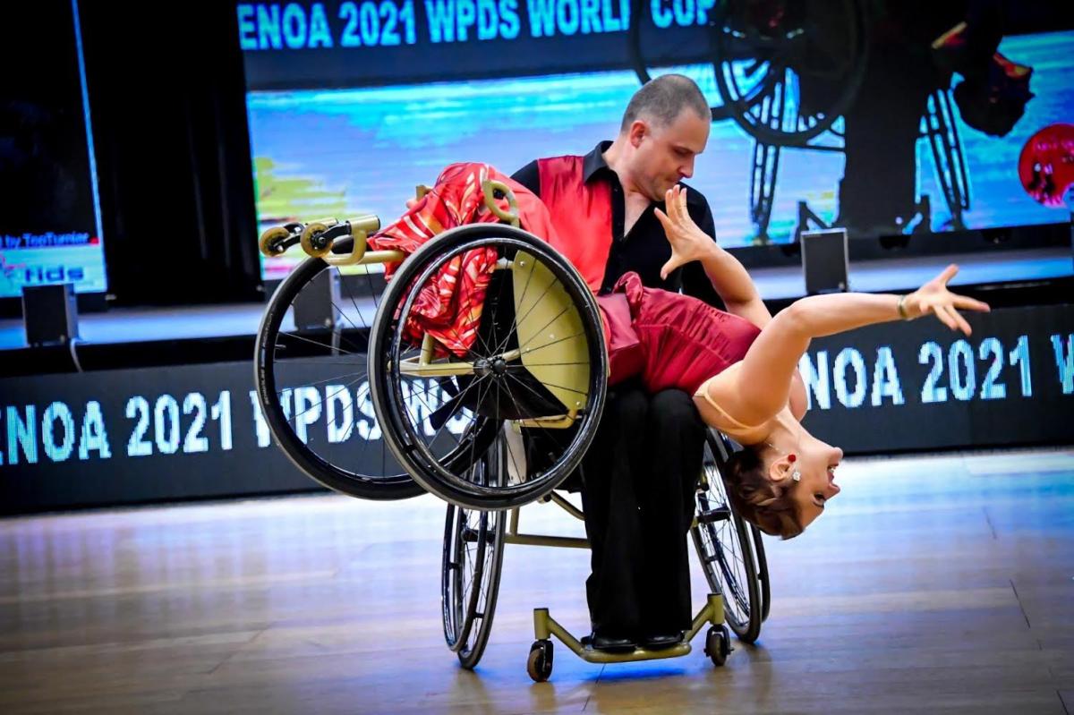 A male wheelchair dancer holding a female wheelchair dancer on his lap