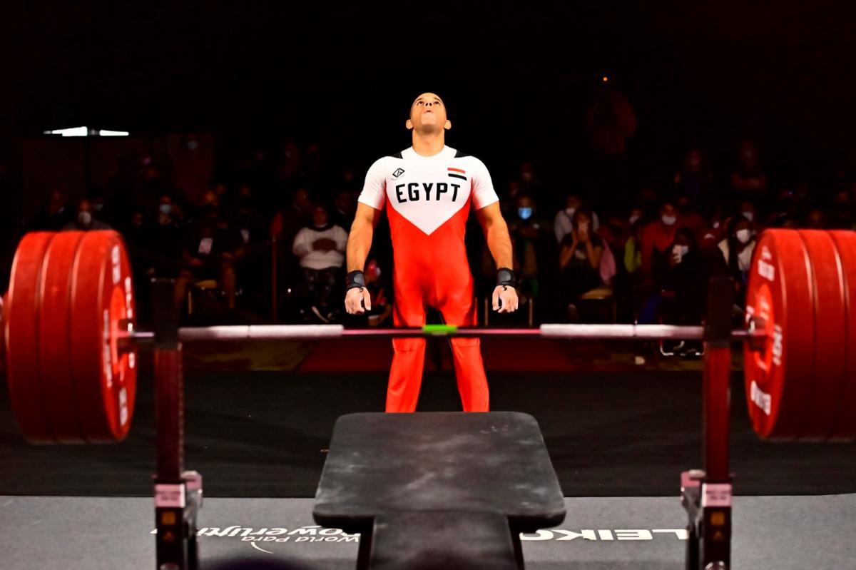 A man looking up and standing in front of a bench press in a Para powerlifting