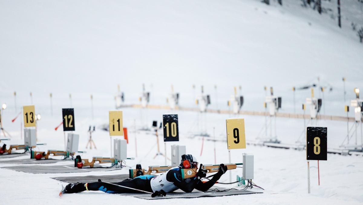 A man lying on the shooting range with a range and aiming.