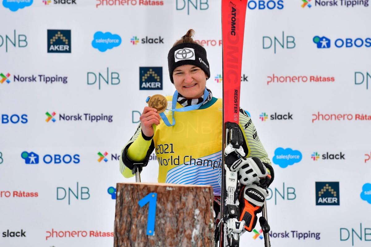 A female skier showing her gold medal in a medal ceremony