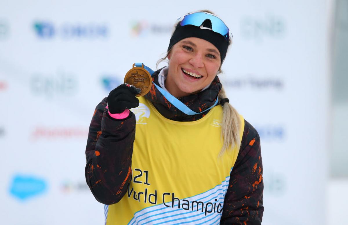 A woman smiling and showing her gold medal