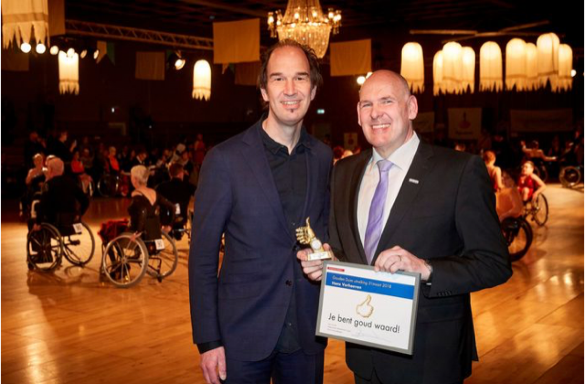 A man smiling with a small trophy next to another man