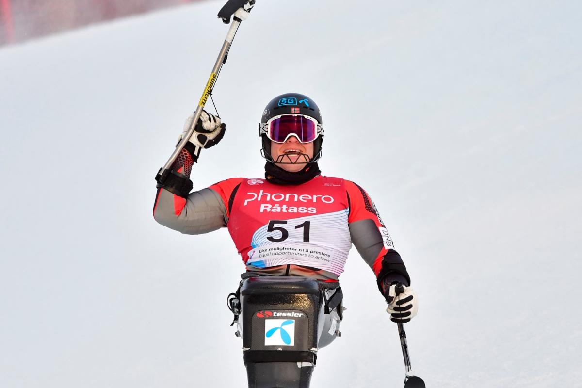 A male sit-skier celebrating in the snow