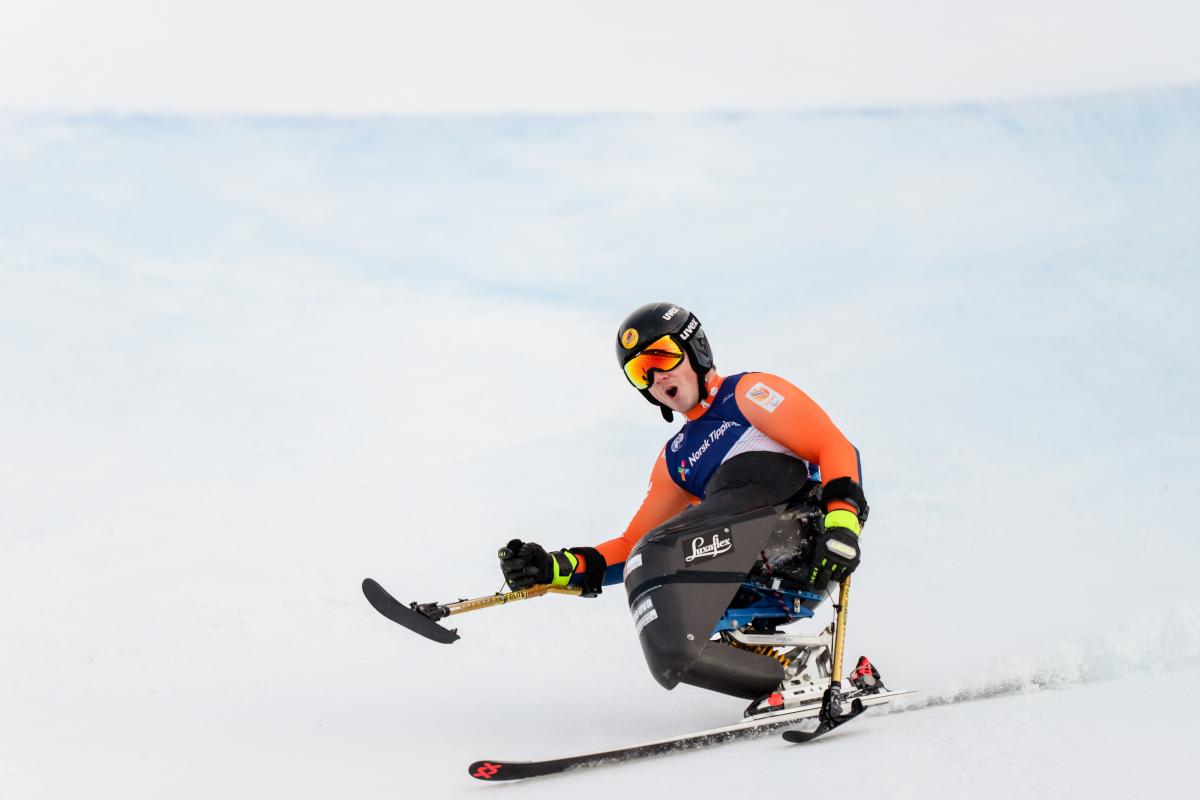 A sit-skier making a turn in a Para alpine skiing competition