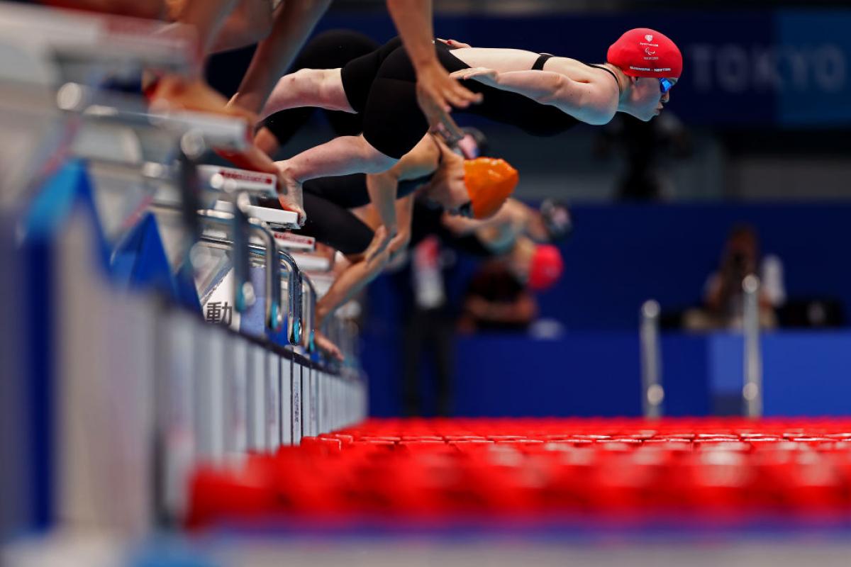 A female swimmers jumping from the starting block ahead of other competitors