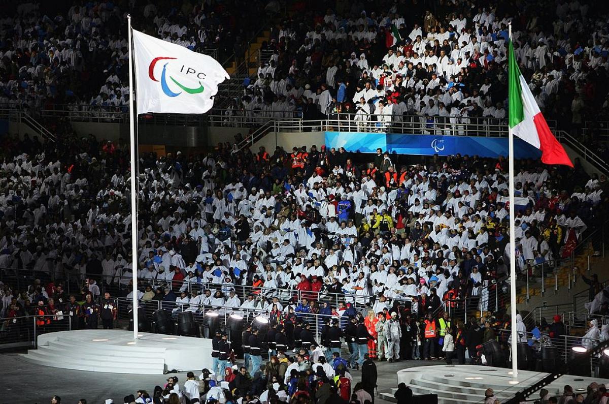 The International Paralympic Committee flag and the Italian national flag fly side by side during the Opening Ceremony of the Turin 2006 Paralympic Winter Games. 