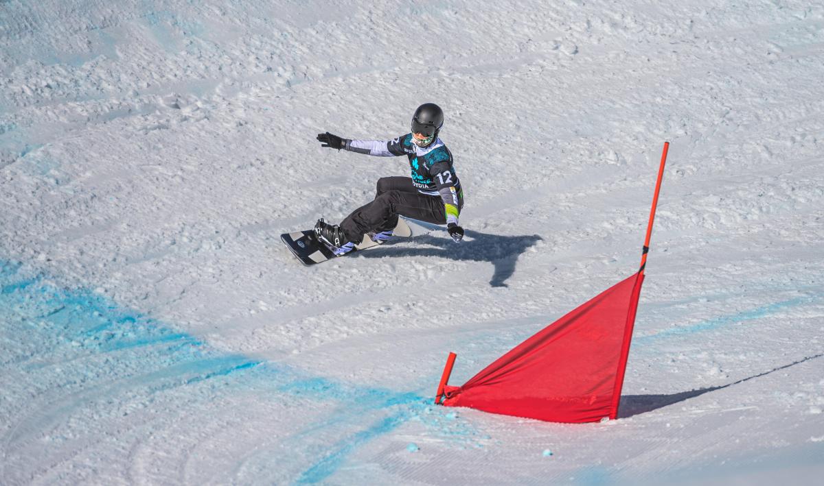 A man on a snowboard with his arms stretched going into the curve.