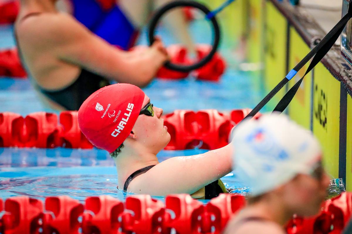 A female swimmer in the pool, hanging onto a rope with both hands before the race start.