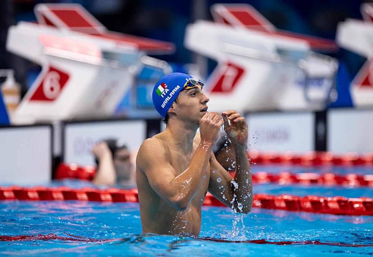 A male swimmer with a blue cap with the Italian flag in a swimming pool
