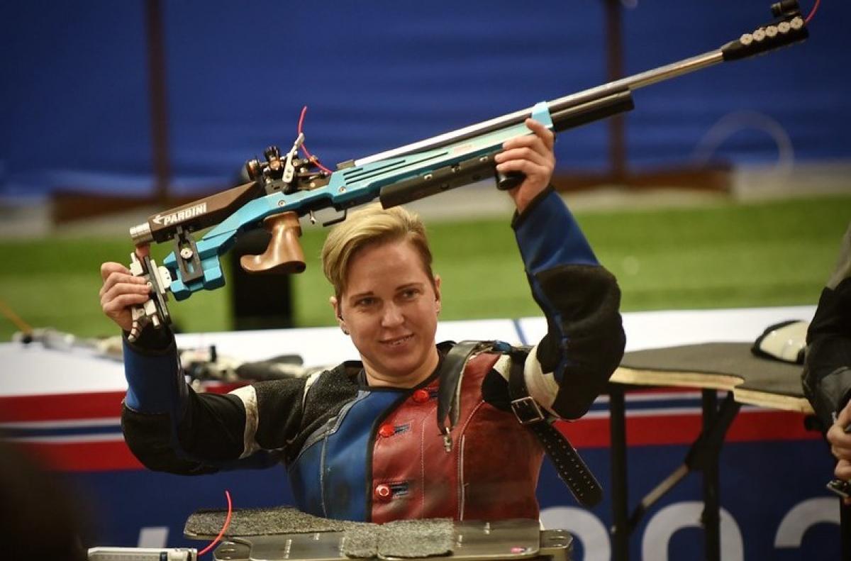 A female shooter raising her competition rifle above her head