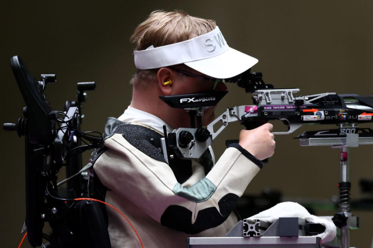 A man in a power chair competing in a shooting event with a rifle