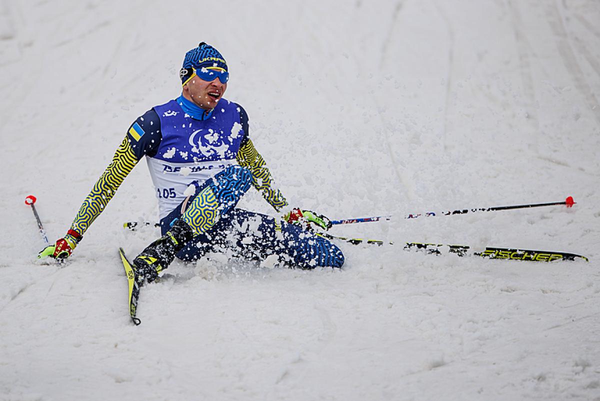 Oleksandr Kazik falls to the ground in a flurry of snow after winning gold at Beijing 2022