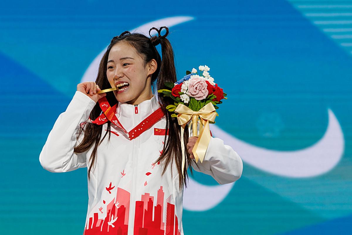 Menqiu Zhang bites her gold medal