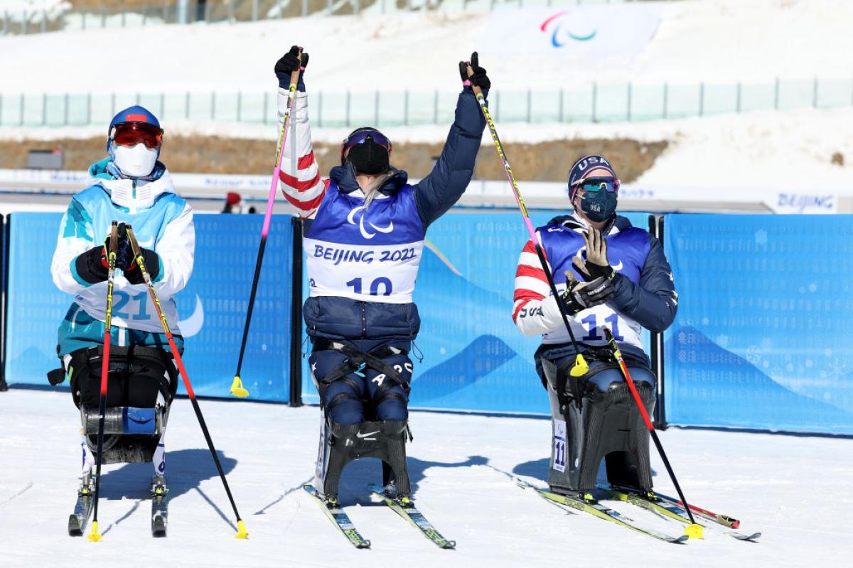 Oksana Masters of United States celebrates winning gold with silver medallist Yilin Shan of China and compatriot bronze medallist Kendall Gretsch in the women's Sprint Sitting Para Biathlon on Day One of the Beijing 2022 Paralympics Winter at Zhangjiakou National Biathlon Centre. 