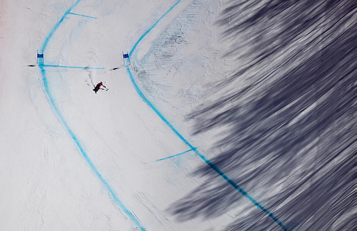 A Para Alpine sit-skier makes their way down the course during training in the shadow of the trees