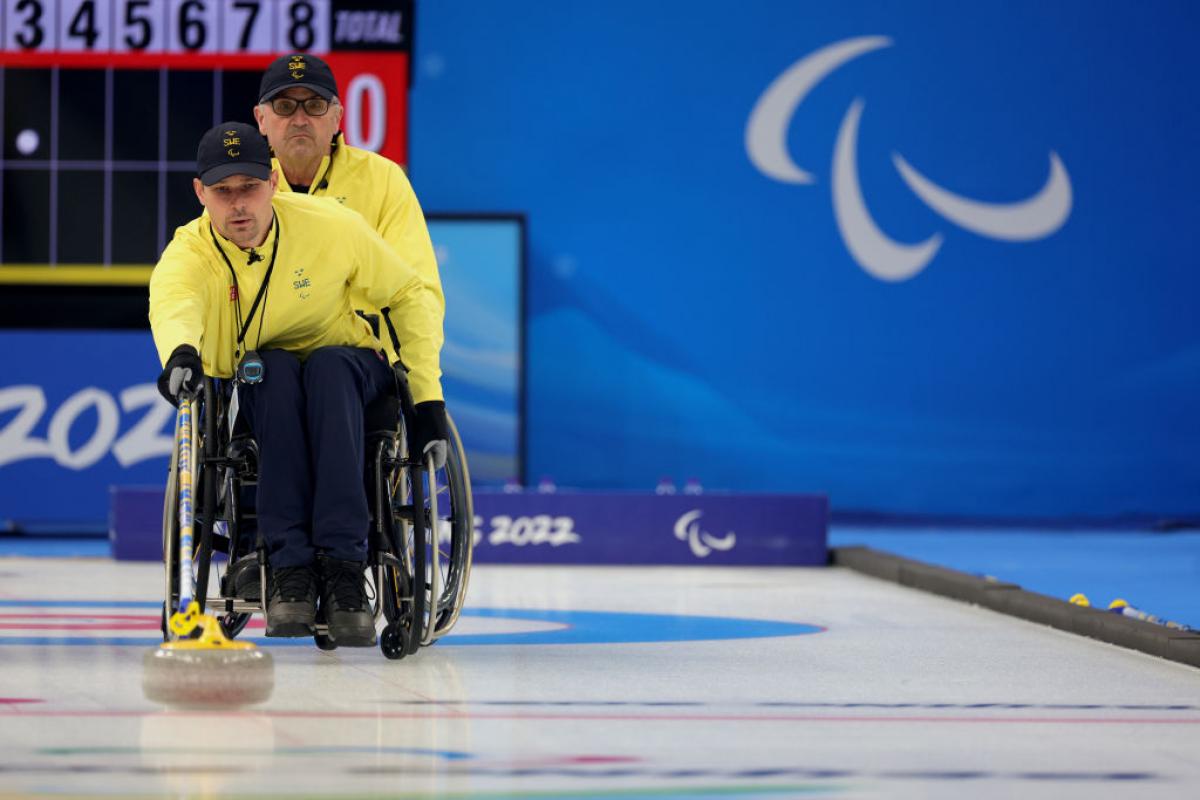 A Swedish wheelchair curler pushes the stone forward