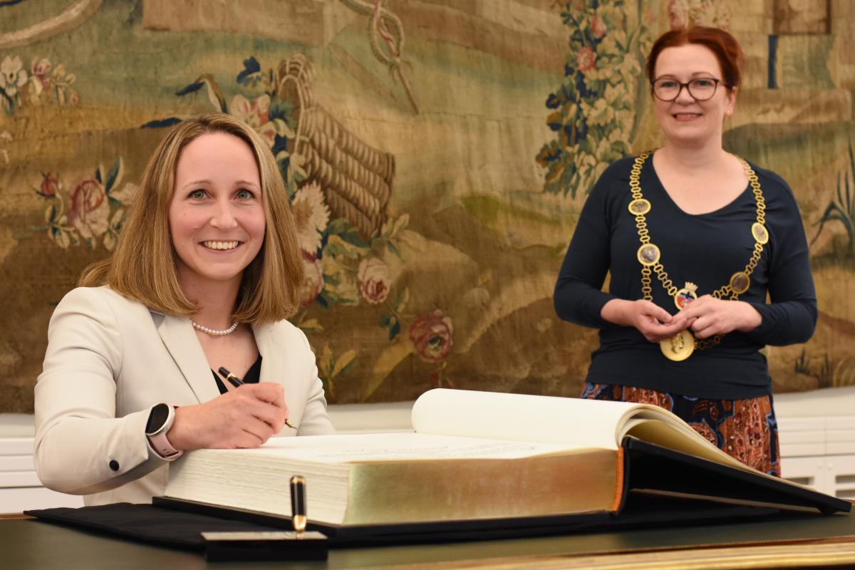 Annika Zeyen signs the Golden Book of Bonn as Bonn Mayor smiles behind