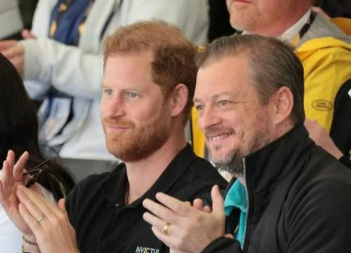 Prince Harry and IPC President Andrew Parsons sitting next to each other and clapping while watching the Invictus Games