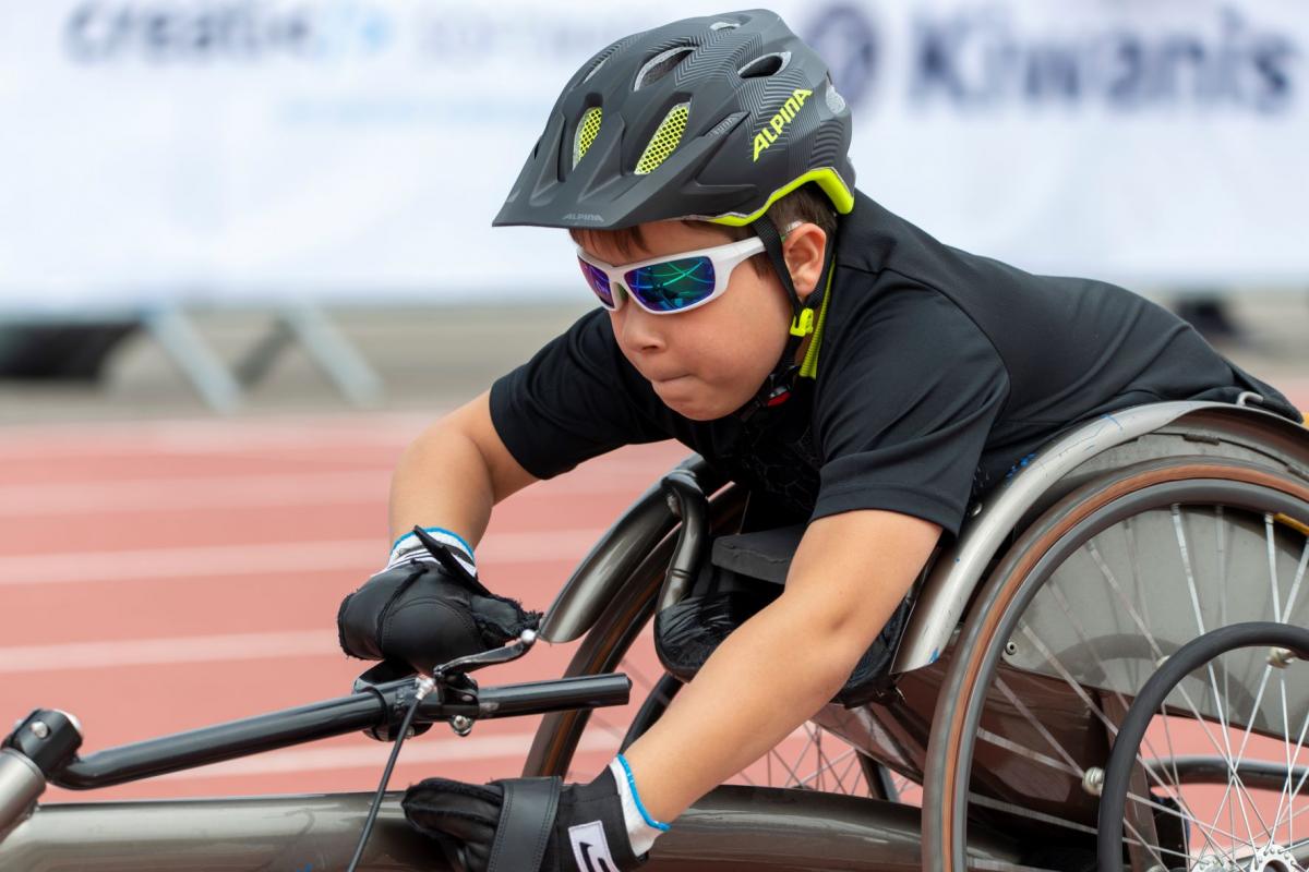 A close-up of Adrian Ruf as he pushes forward in his racing wheelchair with a look of determination on his face.