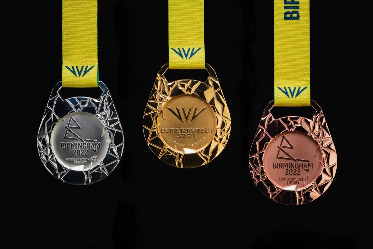 Three medals, gold, silver and bronze, are featured on a black background, each medal having a unique embossed design that symbolises an aerial map of the host region's road and canal network. 