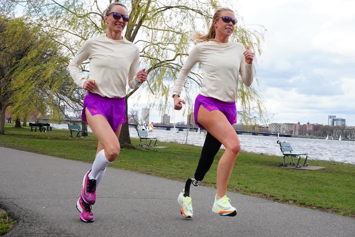 Adrianne Haslet and Shalane Flanagan wear matching beige and purple outfits as they run along the bay during training for the 2022 Boston Marathon.