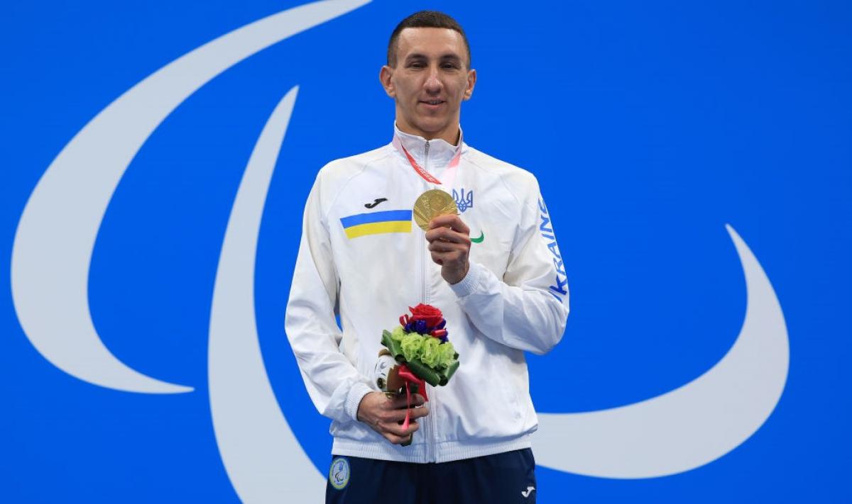 Image of a male Para swimmer in the podium with his gold medal and his flowers