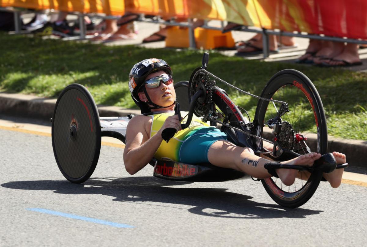 Lauren Parker, wearing the Australian kit but no shoes, rides her handbike on a cement road during the women's PTWC final at the 2018 Commonwealth Games.