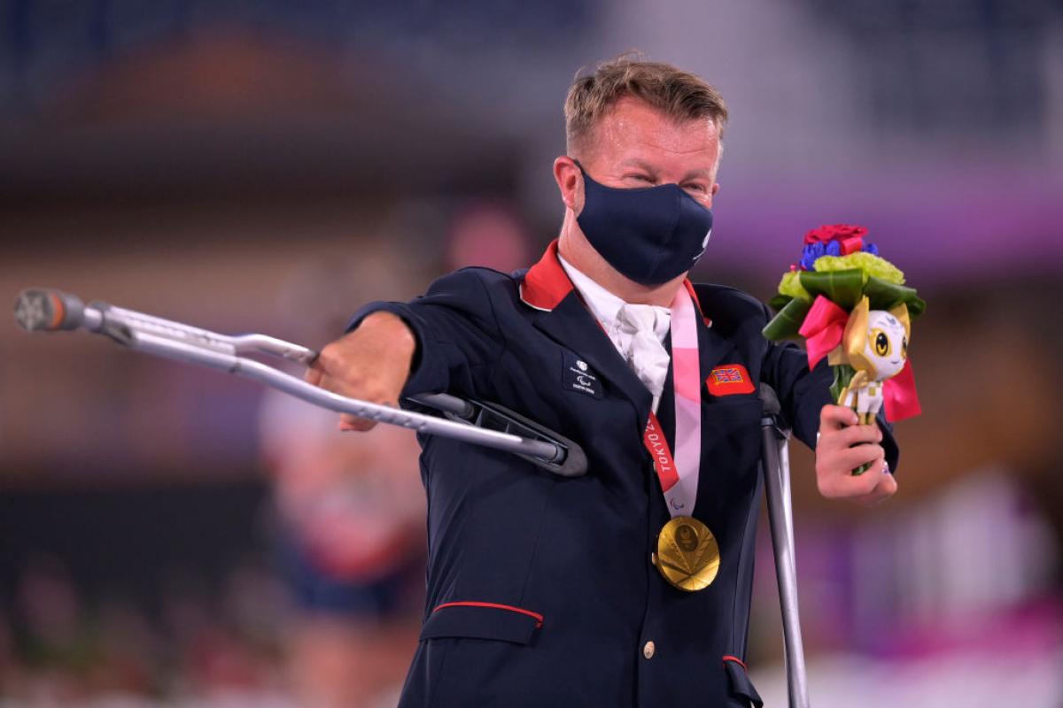 Sir Lee Pearson waves his crutch in celebration after receiving his gold medal at a victory ceremony in Tokyo.
